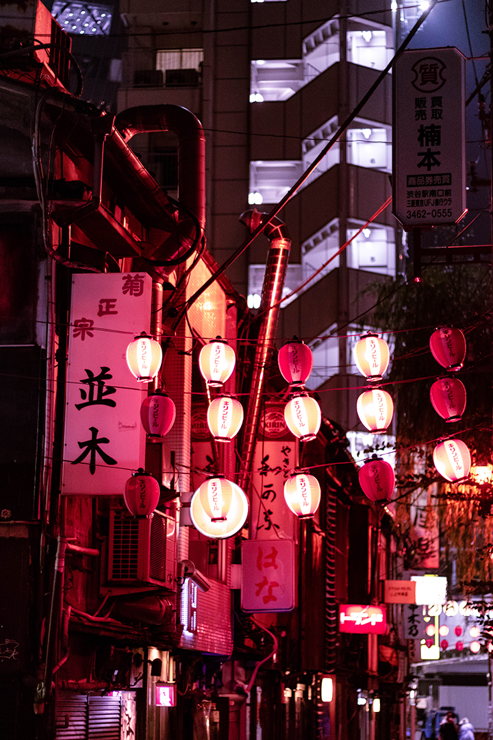 Red Japanese lanterns hanging in an alley.